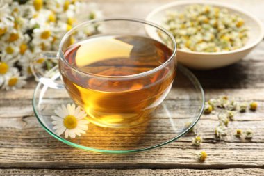 Cam bardakta romatik çay ve ahşap masada papatya çiçekleri, yakın plan.