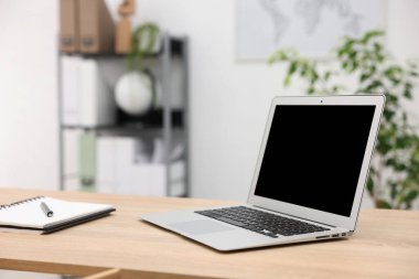 Ofisteki ahşap masada dizüstü bilgisayarı ve kırtasiyesi olan şık bir iş yeri.