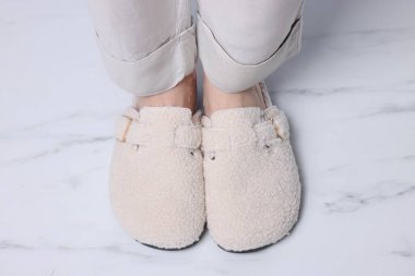 Beyaz mermer zeminde, yumuşak terlikli kadın, yakın plan.