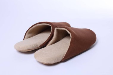 Beyaz arka planda şık kahverengi terlikler, yakın plan.