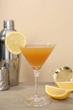 Cam bardakta limon kokteyli ve ahşap masada bej arka planda barmen teçhizatı.
