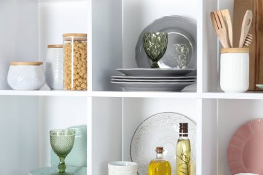 Farklı bulaşık takımları, bardaklar ve diğer mutfak gereçleri olan raf ünitesi.