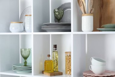 Farklı bulaşık takımları, bardaklar ve diğer mutfak gereçleri olan raf ünitesi.