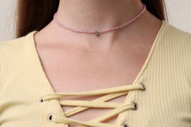 Pembe kolye takan bir kadın, yakın çekim manzaralı.