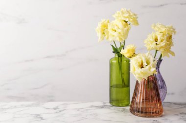 Beyaz mermer masa üzerinde cam vazolarda güzel Eustoma çiçekleri, metin için yer