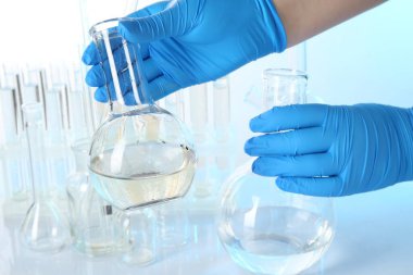 Açık arka planda kirli ve temiz su şişeleri ile bilim adamı, yakın plan