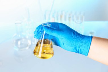 Bilim adamı kirli suyla dolu şişeyi bulanık arka planda tutuyor.