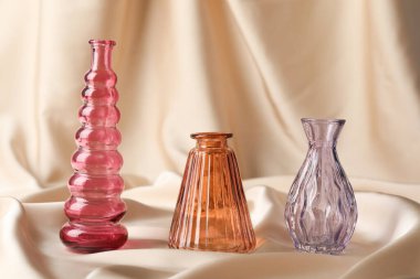 Bej kumaş üzerinde farklı güzel cam vazolar.