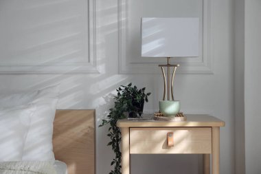 Yatağın içinde lamba ve diğer dekorlarla birlikte komodinin yanında.