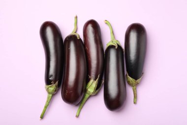 Açık pembe arka planda olgun patlıcanlar.