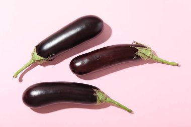 Açık pembe arka planda olgun patlıcanlar.