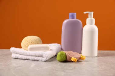 Bebek aksesuarları ve banyo ürünleri gri masada turuncu arka planda