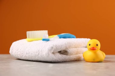 Bebek aksesuarları ve banyo ürünleri gri masada turuncu arka planda, yakın plan