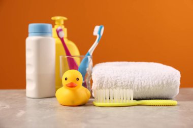 Bebek aksesuarları ve banyo ürünleri gri masada turuncu arka planda, yakın plan