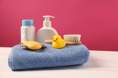 Bebek aksesuarları ve banyo ürünleri pembe arka plana karşı beyaz ahşap masa üzerinde