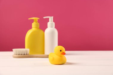Bebek aksesuarları ve banyo ürünleri beyaz ahşap masa üzerinde pembe arka plan, metin için yer