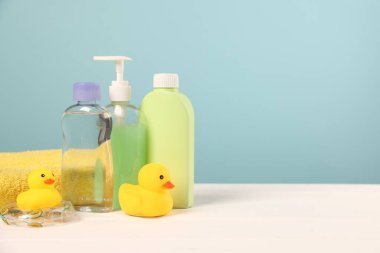 Bebek aksesuarları ve banyo ürünleri beyaz ahşap masa üzerinde açık mavi arkaplan, metin için yer