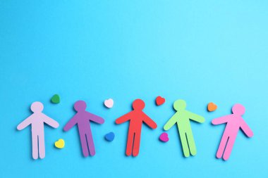 Hoşgörü konsepti. Renkli insan figürleri ve açık mavi arka plandaki kalpler, düz yatıyordu. Metin için boşluk