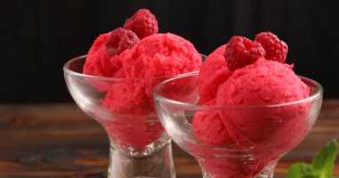 Tatlı kaselerinde ahşap masada nefis ahududu şerbeti, siyah arka planda kamera sağa hareket ediyor.