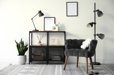 Şık gri koltuk, raf ünitesi ve ev bitkileri. İç tasarım