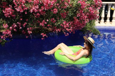 Güneşli bir günde yüzme havuzunda şişme halkalı bir kız.