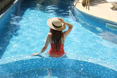 Yüzme havuzunda hasır şapkalı bir kız.