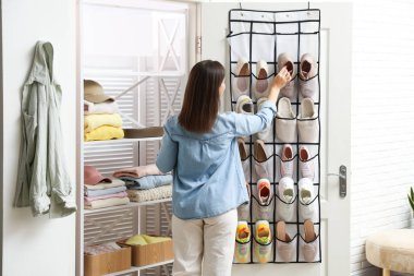 Bir kadın spor ayakkabısını evde, arka planda düzenleyiciye takıyor. Ayakkabı deposu