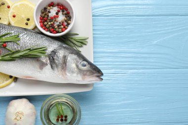 Mavi ahşap masadaki baharatlı taze çiğ deniz kabuğu balığı, yazı için düzlük ve boşluk. Deniz ürünleri lezzetleri.