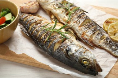 Beyaz ahşap masada salata ve limonla servis edilen lezzetli kavrulmuş deniz kabuğu balığı. Ev yapımı deniz ürünleri yemeği.