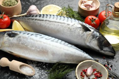 Siyah masada taze çiğ uskumrular ve baharatlar, yakın plan. Deniz ürünleri lezzetleri.