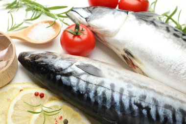 Beyaz masada taze çiğ uskumrular ve baharatlar, yakın plan. Deniz ürünleri lezzetleri.