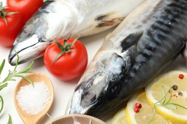 Beyaz masada taze çiğ uskumrular ve baharatlar, yakın plan. Deniz ürünleri lezzetleri.