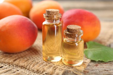 Şişelerdeki yağlar ve ahşap masadaki olgun kayısılar, yakın çekim.