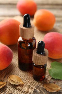 Şişelerdeki, tohumlardaki ve olgun kayısılardaki yağlar ahşap masada, yakın plan.