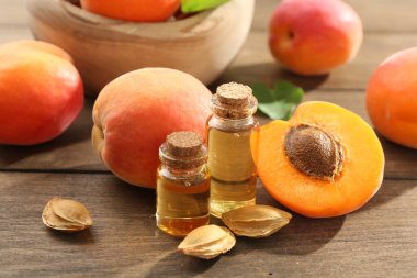 Şişelerdeki, tohumlardaki ve olgun kayısılardaki yağlar ahşap masada, yakın plan.