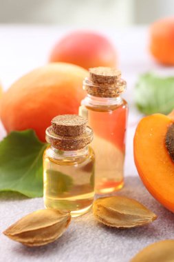 Şişelerdeki, tohumlardaki ve olgun kayısılardaki yağlar açık dokulu masalarda, yakın çekim.