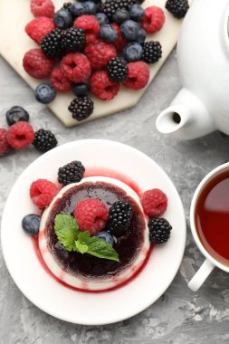 Böğürtlenli ve reçelli leziz panna cotta açık gri masada, düz yatıyordu.