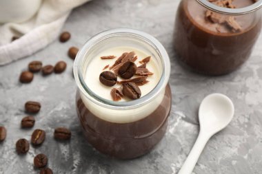 Çikolata parçalı lezzetli panna cotta ve gri desenli masada kahve çekirdekleri, yakın plan.