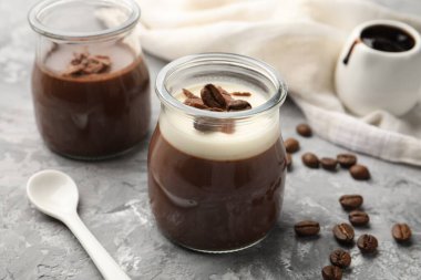 Çikolata parçalı lezzetli panna cotta ve gri desenli masada kahve çekirdekleri, yakın plan.