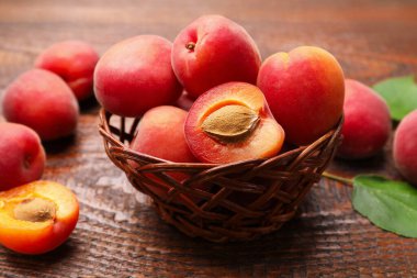 Hasır sepetin içinde nefis olgun kayısılar ahşap masanın üstünde, yakın plan.