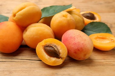 Tahta masada taze kayısılar ve yeşil yapraklar yığını. Yakın plan.