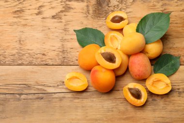 Bir sürü taze kayısı ve yeşil yapraklar ahşap masada, düz yerde. Metin için boşluk