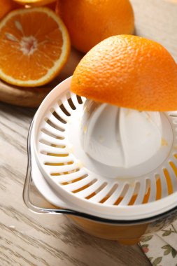 Meyve suyu. Meyve sıkacağı ve taze portakallar ahşap masada, yakın plan.