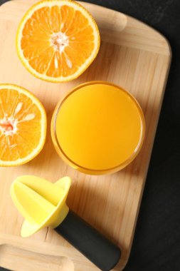 Bardakta taze portakal suyu, siyah masada meyve suyu ve meyve sıkacağı.