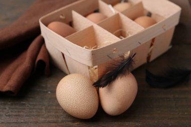 Yumurta tepsisindeki çiğ tavuk yumurtaları ahşap masada, yakın plan.