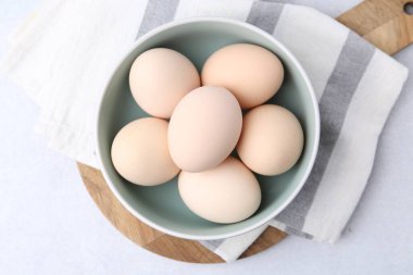 Tabakta çiğ tavuk yumurtası, beyaz masa, üst manzara.