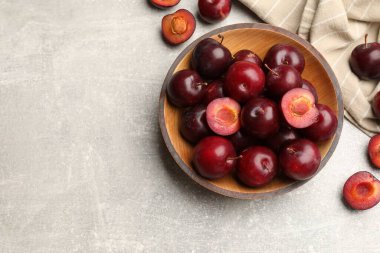 Olgun kiraz erikleri ve gri desenli masada bir kase, düz uzanmış. Metin için boşluk