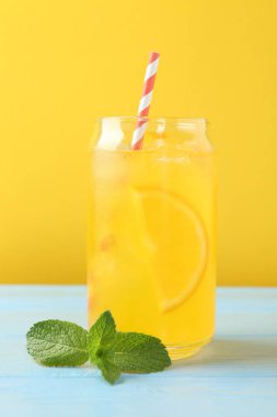 Soda tazeleniyor, portakal dilimli cam ve nane şekerli açık mavi ahşap masa, yakın plan.