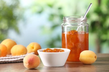 Lezzetli kayısı reçeli ve ahşap masada taze meyveler bulanık arka planda, yakın plan