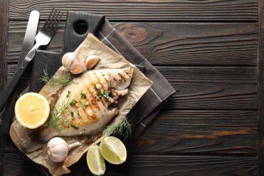 Ev yapımı deniz ürünleri yemeği. Ahşap masada servis edilen baharatlı, kavrulmuş pisi balığı. Metin için boşluk